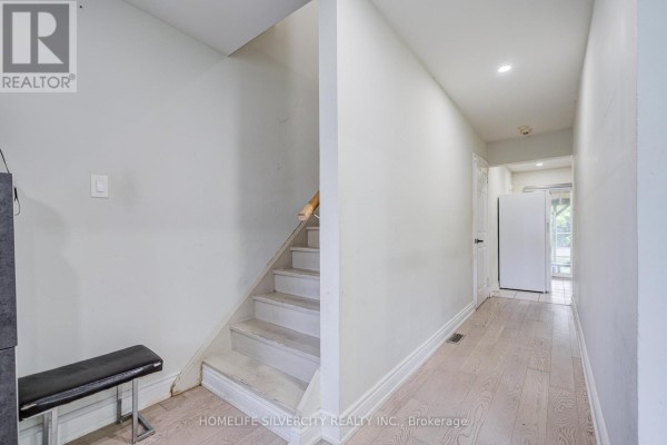 Interior hallway with a bench, staircase to the left, and a door at the end. - 160 Purvis Crescent, Toronto