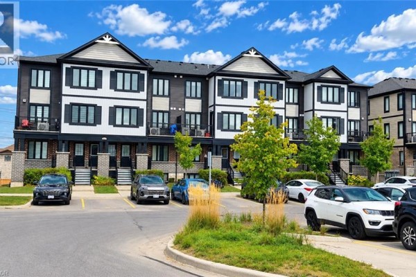 Living room with a dark brown leather couch, TV, and wood-look flooring. - 160 Rochefort Street Unit# C14, Kitchener