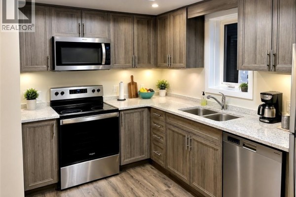 Home office with a wooden desk, black office chair, and a large window overlooking townhouses. - 160 Rochefort Street Unit# C14, Kitchener