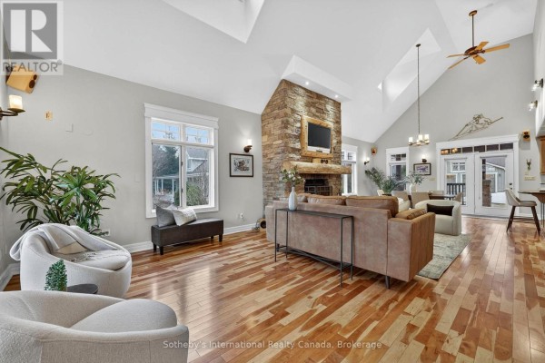 Living room with stone fireplace, vaulted ceiling, and hardwood floors - 160 Sunset Boulevard Blue Mountains