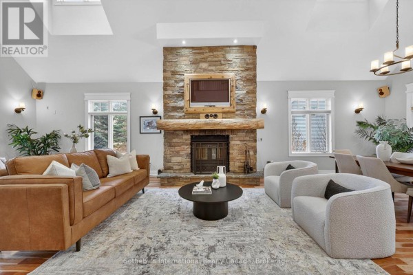 Living room with stone fireplace, leather sofa, and bouclé armchairs - 160 Sunset Boulevard Blue Mountains