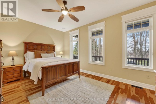 Wooden bed, nightstand, and hardwood floors with ceiling fan and large windows - 160 Sunset Boulevard Blue Mountains