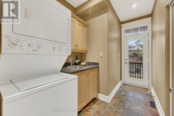 Stackable washer/dryer, sink, and cabinetry in laundry room with deck access - 160 Sunset Boulevard Blue Mountains