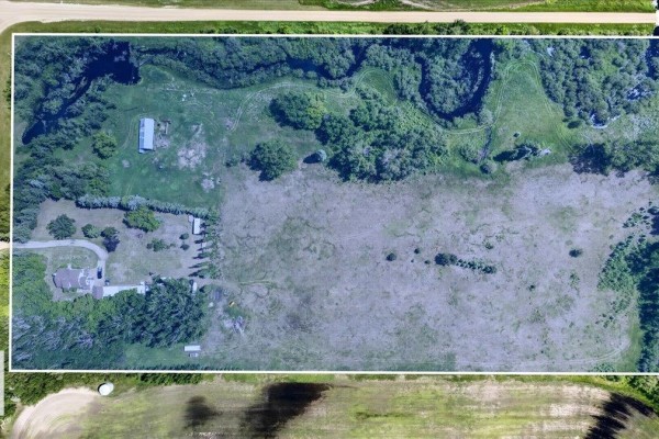 Aerial view of a rural property with a house, garage, outbuildings, and wooded areas. - 160005 Twp 540, Rural Lamont County