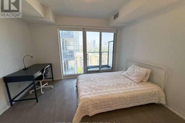 Bedroom with a desk and chair, a bed, and a sliding glass door to a balcony overlooking the city. - 1601 - 251 Jarvis Street, Toronto