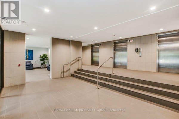 Building lobby with beige tiles, stairs, metal handrails, and three stainless steel elevators. - 1601 - 665 Bathgate Drive, Ottawa