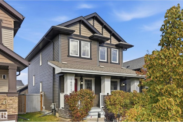 Side view of a two-story house with dark brown siding and a covered porch. - 16012 11 Av Sw Sw, Edmonton