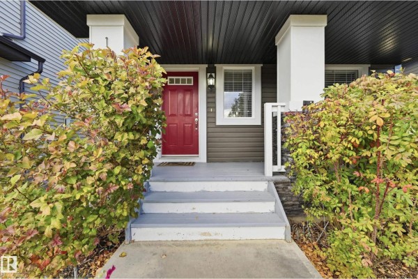 Close-up of a front porch with gray steps and a red front door. - 16012 11 Av Sw Sw, Edmonton