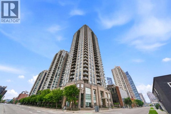 Wide exterior shot of the apartment building complex with surrounding city buildings and blue sky. - 1602, 1111 10 Street Sw, Calgary