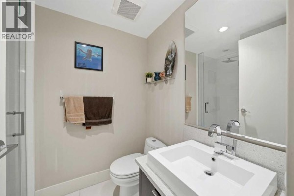 A modern bathroom with a white vessel sink, silver faucet, and a glass-enclosed shower. - 1602, 1111 10 Street Sw, Calgary