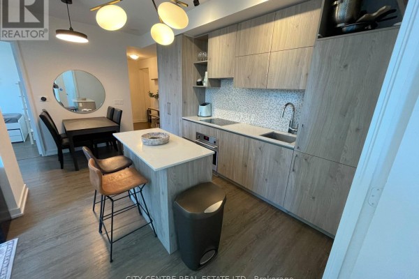 Kitchen island with breakfast bar stools and modern cabinetry, facing dining area. - 1602 - 1 Yorkville Avenue, Toronto