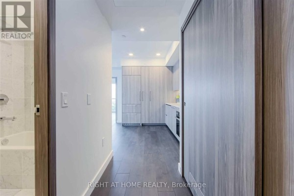 Interior view of a hallway with a bathroom on the left and a kitchen visible ahead. - 1602 - 95 Mcmahon Drive, Toronto