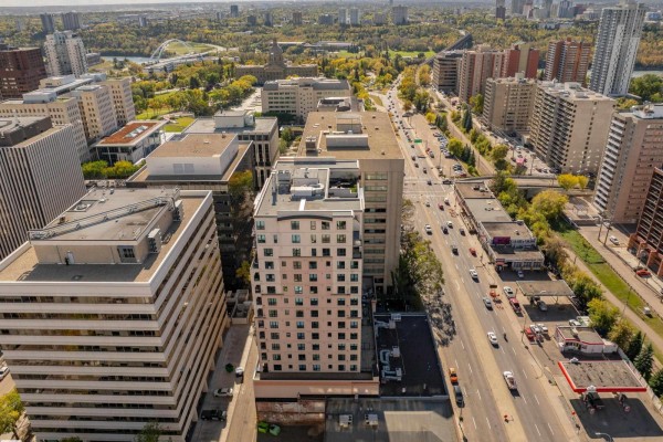 Aerial view of city buildings and a tree-lined street under a partly cloudy sky. - #1603 9939 109 St Nw, Edmonton