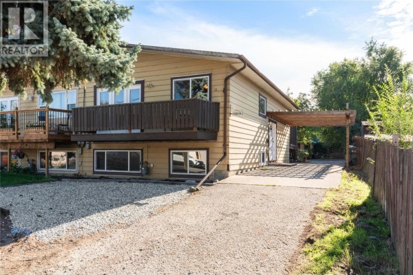 Close-up exterior view of a beige duplex with a driveway and covered carport. - 1603b 45th Street, Vernon