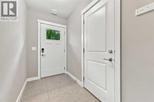 Interior entryway with beige tiled floor, white doors, and a small window. - 1604, 32 Horseshoe Crescent, Cochrane