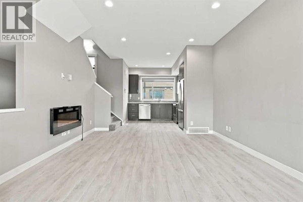 Open concept living area with grey walls, light wood floors, and a black electric fireplace. - 1604, 32 Horseshoe Crescent, Cochrane