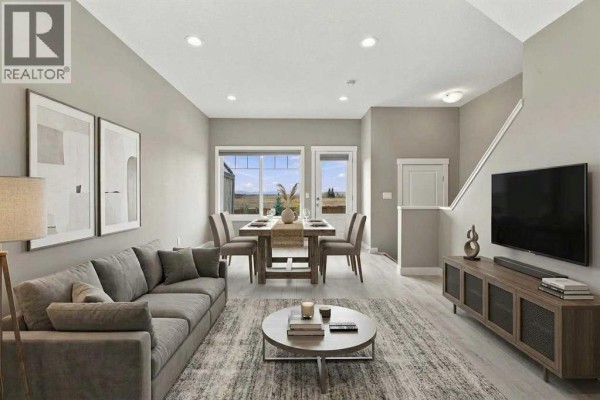 Living and dining area with grey sectional sofa, round coffee table, and dining set by window. - 1604, 32 Horseshoe Crescent, Cochrane
