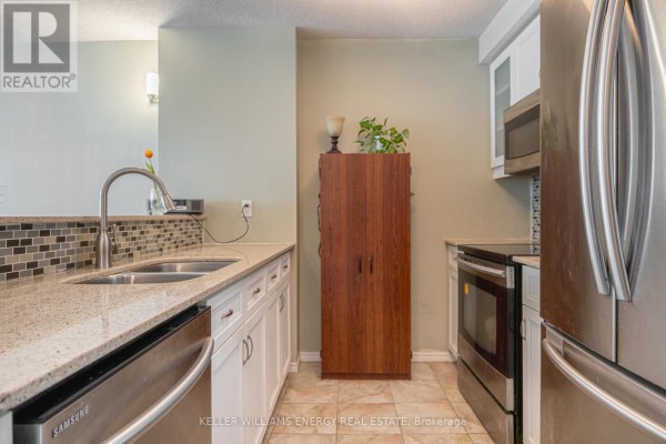Close-up of kitchen area featuring double sink, wooden cabinet, and tile flooring - 1604 - 10 Yonge Street, Toronto