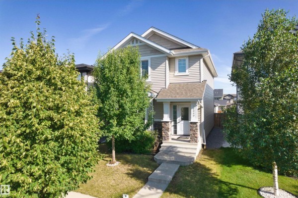 Front view of a two-story house with landscaping and mature trees. - 16040 11 Av Sw, Edmonton