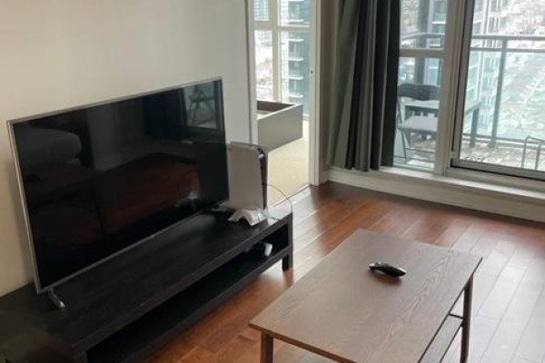 Living room with a flat-screen TV on a black media console and a coffee table. - 1605 - 4070 Confederation Parkway W, Mississauga