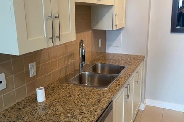 Kitchen with cream-colored cabinets, a double sink, and a tiled backsplash. - 1605 - 4070 Confederation Parkway W, Mississauga