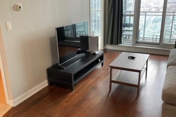 Living room with hardwood floors, a television, coffee table, and balcony view. - 1605 - 4070 Confederation Parkway W, Mississauga