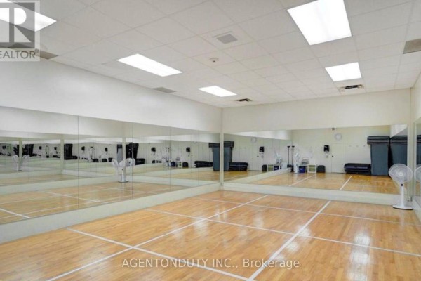 Empty exercise room with wood floor, mirrors on walls, and fluorescent lighting. - 1605 - 65 Harbour Square, Toronto