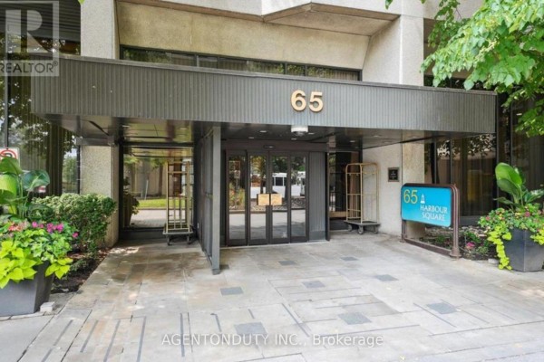 Building entrance with glass doors, canopy, and planters with flowers. - 1605 - 65 Harbour Square, Toronto