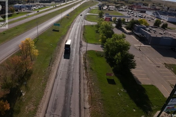 Aerial view of a highway with a semi-truck driving on the right lane and commercial buildings on the right side. - 1605 North Service Road E, Swift Current