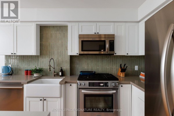 Close-up of a kitchen faucet with a gooseneck spout and a vertical green tile backsplash. - 1606 - 12 Sudbury Street, Toronto