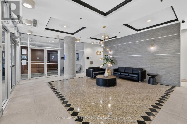 Apartment building lobby with black couches, circular coffee table, and modern chandelier. - 1606 - 90 Landry Street, Ottawa