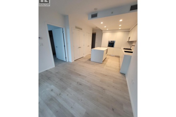 Open concept living area with white kitchen, island, and light wood floors. - 1606 3809 Evergreen Place, Burnaby