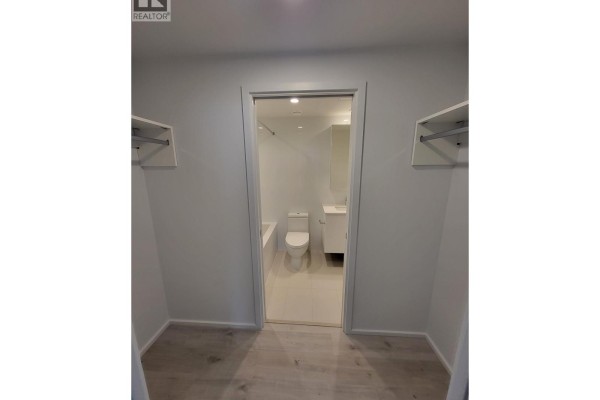 Walk-through closet with open shelving leading to a white bathroom with a bathtub. - 1606 3809 Evergreen Place, Burnaby