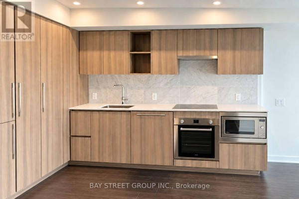 View of the apartment kitchen with light wood cabinets, white countertops, and stainless steel appliances. - 1608 - 19 Bathurst Street, Toronto