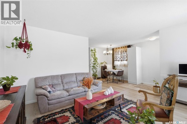 Living room with white walls, large TV, fireplace, and decorative rug. - 1608 Vickies Avenue, Saskatoon