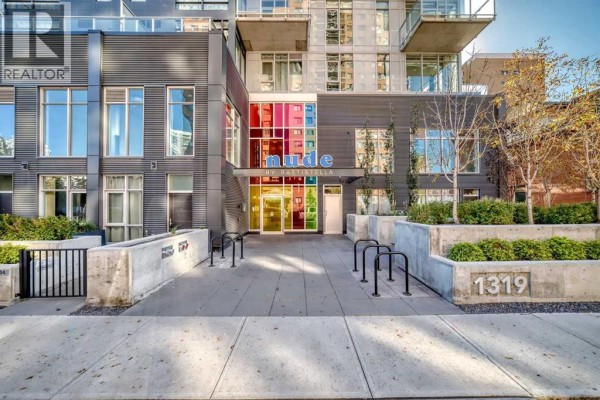 Entrance to the 'Nude by Pattisella' building with colorful glass accents and concrete landscaping. - 1609, 1319 14 Avenue Sw, Calgary