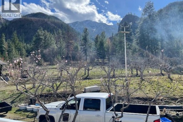 View of bare trees with pink blossoms in a field, and a white pickup truck. - 1609 Trans Canada Highway, Lytton