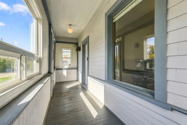 Covered porch with wood floors, white paneled walls, and large windows. - 161 Atlantic Avenue, Winnipeg