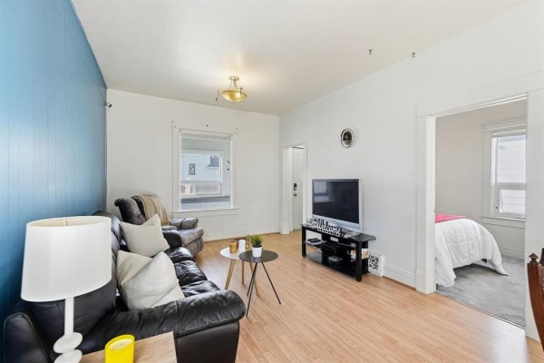 Living room with a doorway leading to a bedroom with a white comforter. - 161 Atlantic Avenue, Winnipeg