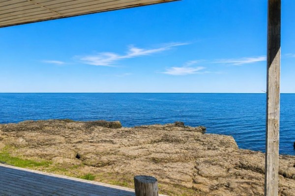 Bedroom with a wooden bed, floral quilt, and window overlooking the sea. - 161 Culloden Wharf Branch, Culloden