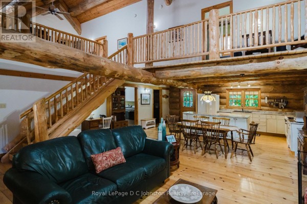 Dining area with wooden table and chairs, facing a large staircase and cabinet. - 161 Grey Street S, Saugeen Shores