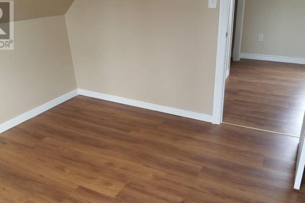 Corner of a room with beige walls and dark wood laminate flooring. - 161 Hanover Street, Summerside