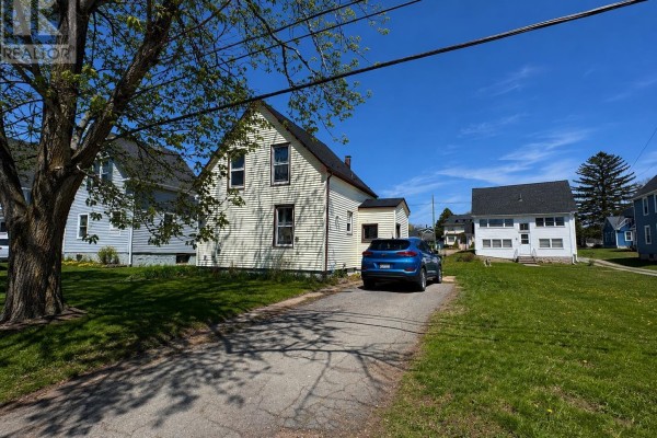 Side view of a two-story white house with a blue SUV in the driveway. - 161 Hanover Street, Summerside
