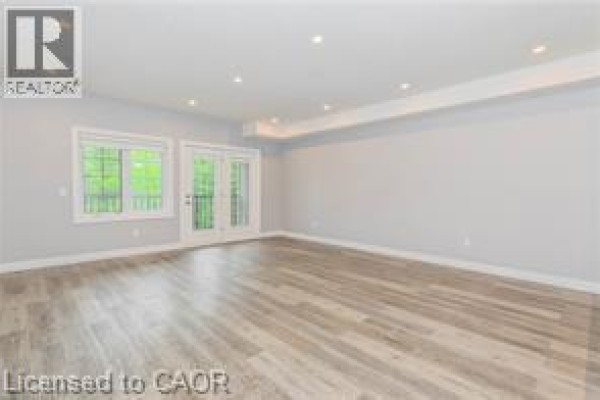 Living room with light grey walls, wood-look flooring, and double glass doors. - 161 Ottawa Street S Unit# 203, Kitchener