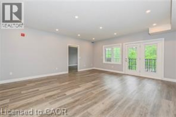 Living room with grey walls, wood-look floors, and doors leading to other rooms. - 161 Ottawa Street S Unit# 203, Kitchener