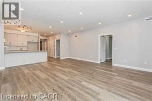 Open concept living area with kitchen island, light grey cabinets, and wood-look flooring. - 161 Ottawa Street S Unit# 203, Kitchener