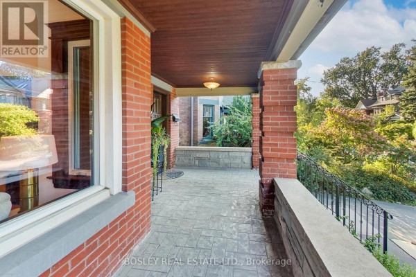 View from the porch showing red brick pillars and a black metal railing. - 161 Westminster Avenue, Toronto