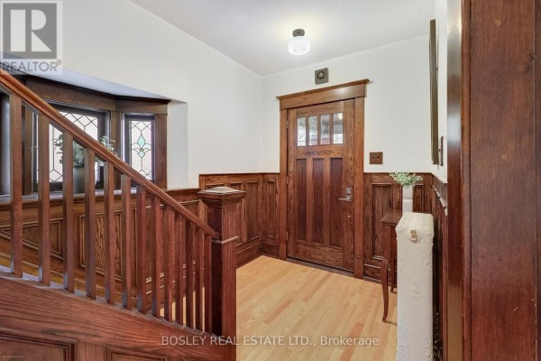 Interior entryway with a wooden staircase, wainscoting, and a glass-paned front door. - 161 Westminster Avenue, Toronto