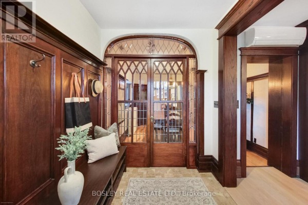 Foyer with wood paneling, a wooden bench, and decorative glass doors leading to a dining room. - 161 Westminster Avenue, Toronto