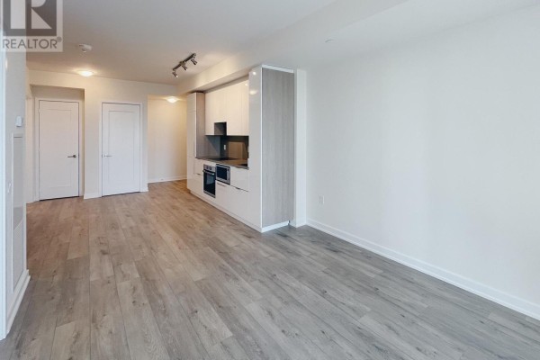 Living area with modern kitchen featuring light cabinets, stainless steel appliances, and grey countertops. - 1610 - 28 Freeland Street, Toronto